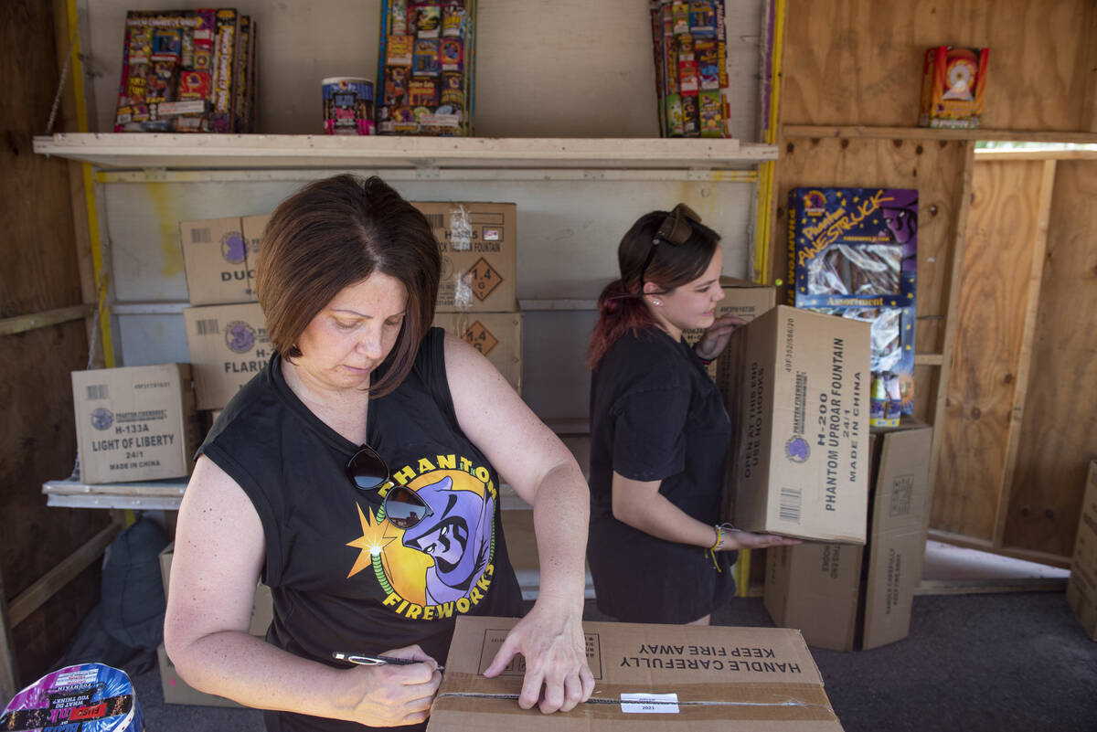 Shellie Moskos, left, and Hannah Dockery unpack and organize boxes of fireworks as they set up ...