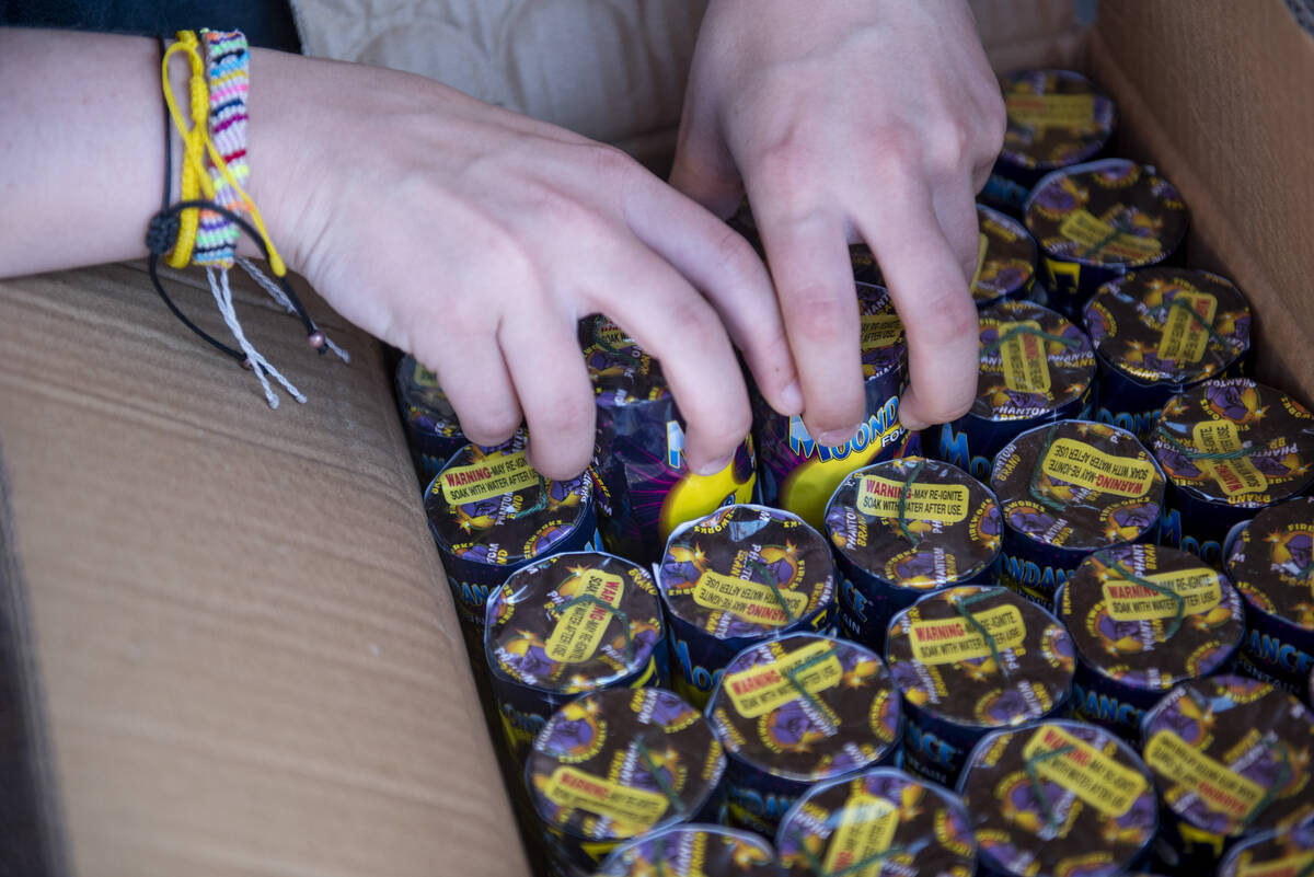 Hannah Dockery unpacks a box of fireworks as she helps set up her organization's Phantom Firewo ...