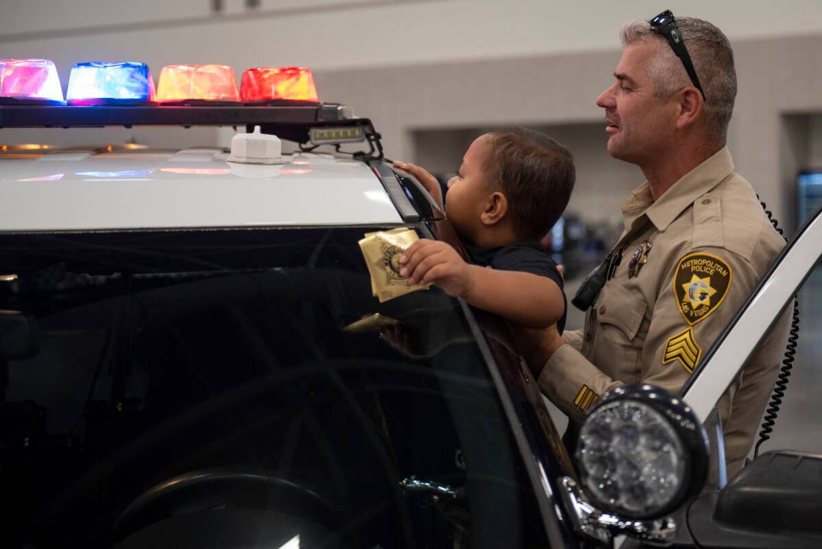 Metro Police Sargent Mark Zemsta shows Sean Moeileolo, 6, the lights on a police cruiser during ...