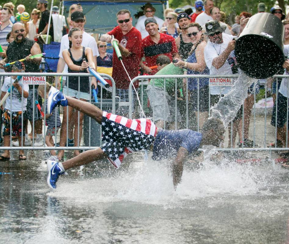 In this Thursday, July 4, 2013, file photo, Roger Johnson, center, is doused with water as he d ...