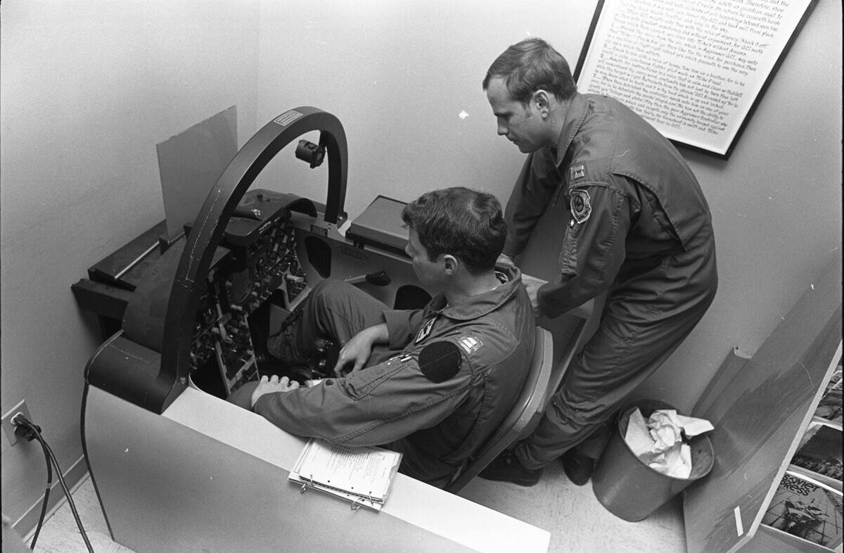 Instructor Captain Scott Van Cleef teaches Captain “Tank” Payne in the pilot’s seat about ...