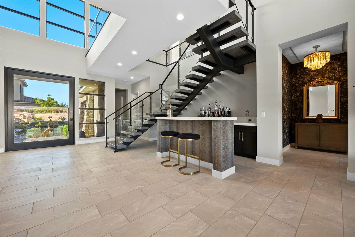 The second floor is accessed through a floating staircase leading to an upper bridge that overl ...