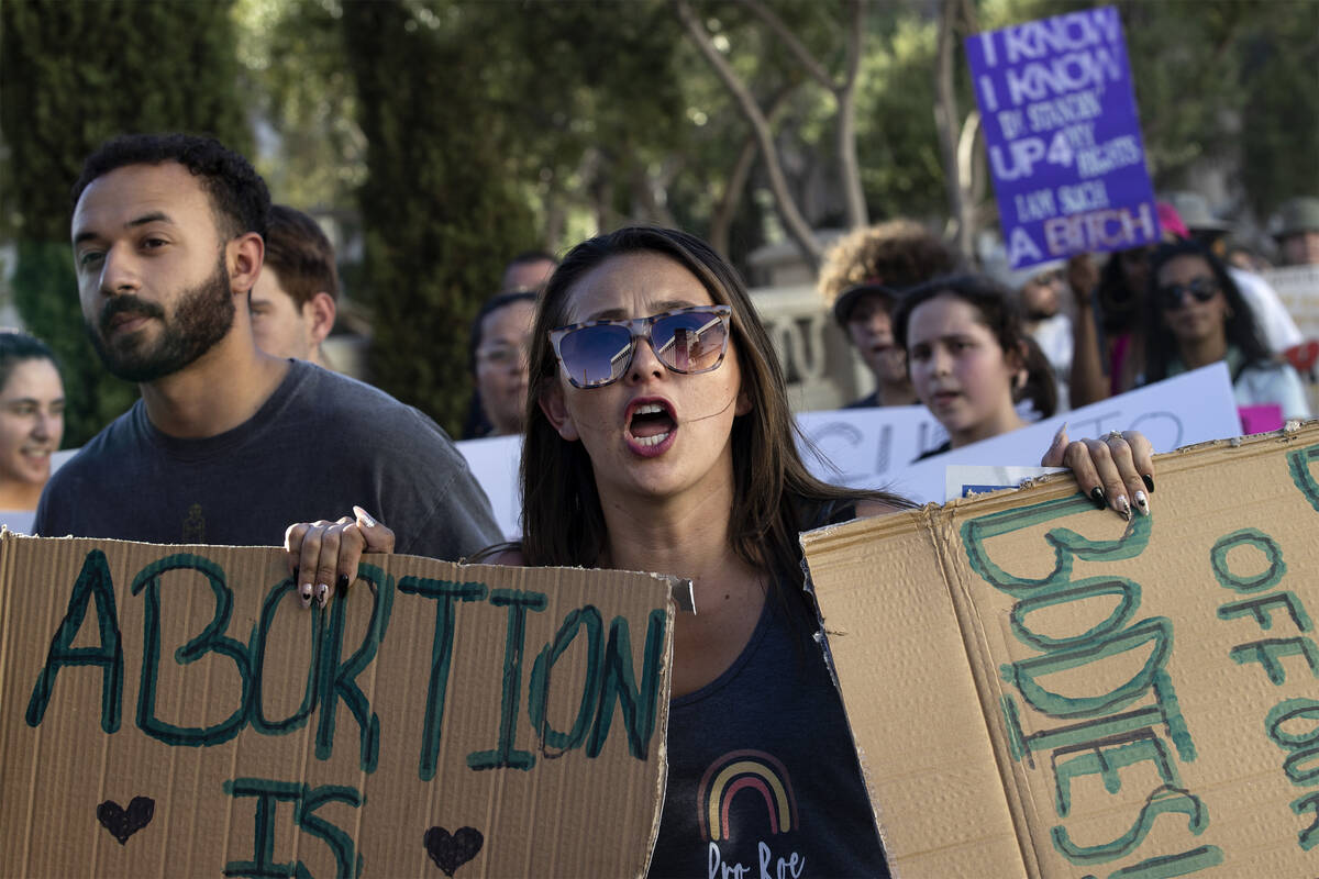 Chelsea Chavez, of Las Vegas, carries signs reading “abortion is healthcare” and ...