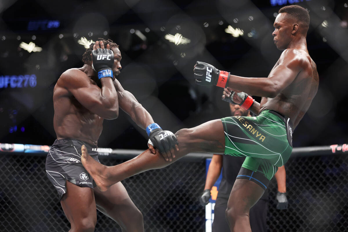 Israel Adesanya, right, throws a kick against Jared Cannonier during the first round of a middl ...