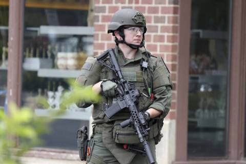 A law enforcement officer watches as people are evacuated from an Anthropologie store in Highla ...