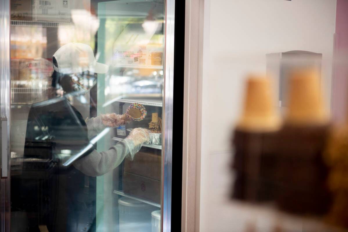 Employee Axel Vega stores specialty waffle cones in the cooler at Cream Me Ice Creamery on Main ...