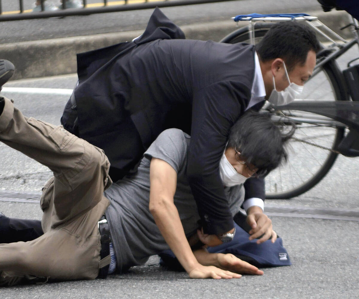 Tetsuya Yamagami, bottom, is detained near the site of gunshots in Nara Prefecture, western Jap ...