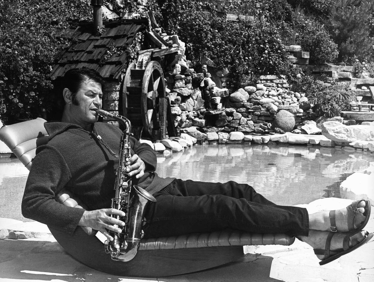 TV and motion picture star Larry Storch relaxes while playing a saxophone poolside at his Holly ...