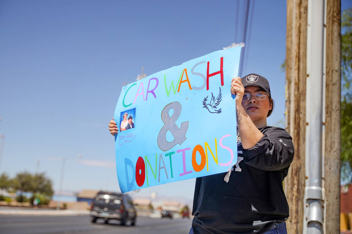 Griselda Gallarzo holds a sign for a car wash fundraiser for the burial of Delia Luna-Rojo and ...