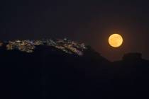 FILE - The strawberry supermoon rises behind the village of Imerovigli on Sandorini's caldera, ...