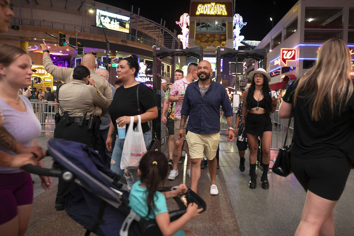 Security officers screen people as they walk through a metal detector before entering the Fremo ...
