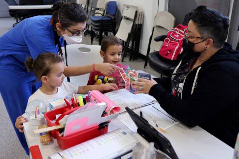 Mais Yacoub helps her 3-year-old twins Quincy, left, and Luca, pick Band-Aids from public healt ...