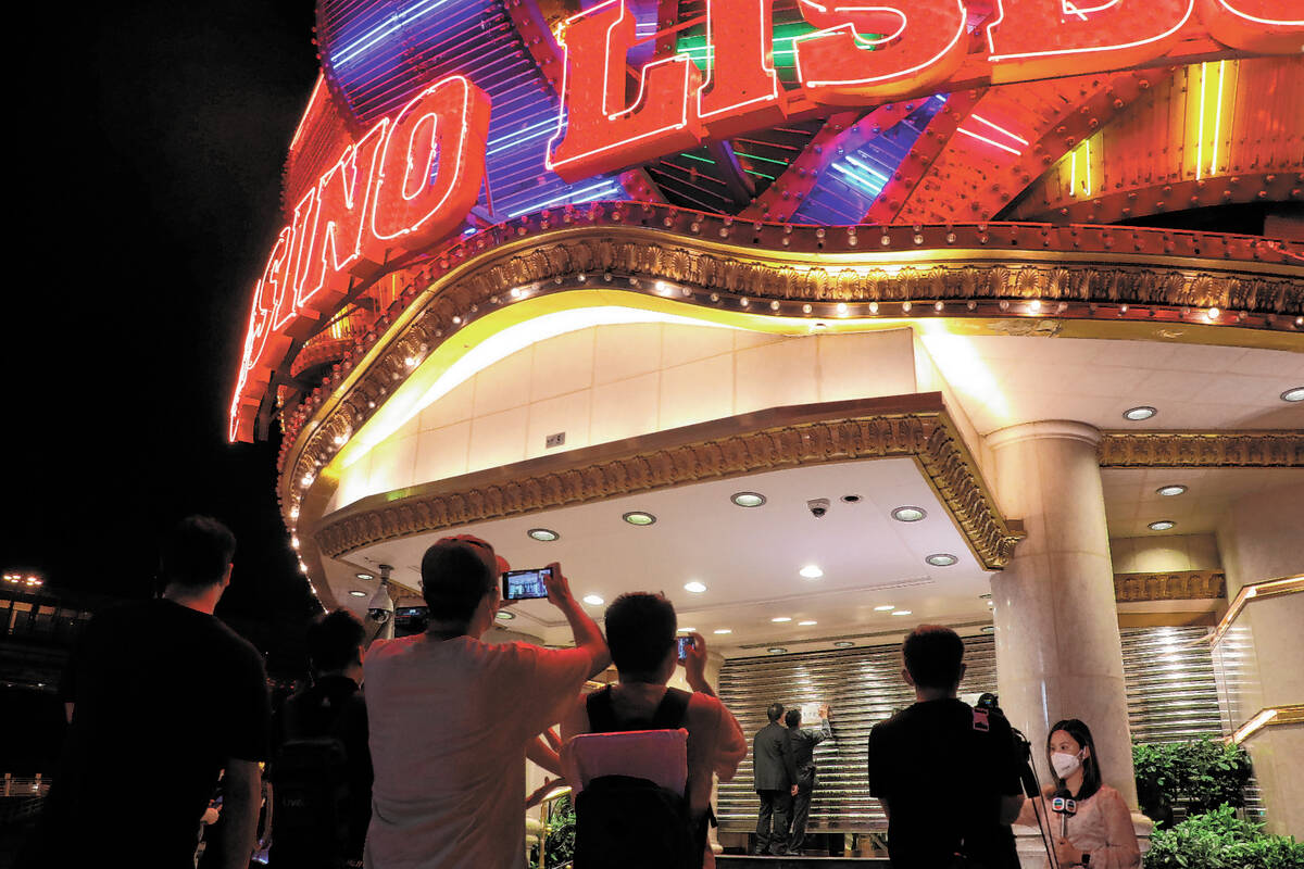 People take photos as security closes the shutters at Casino Lisboaʡt midnight on Monday, ...
