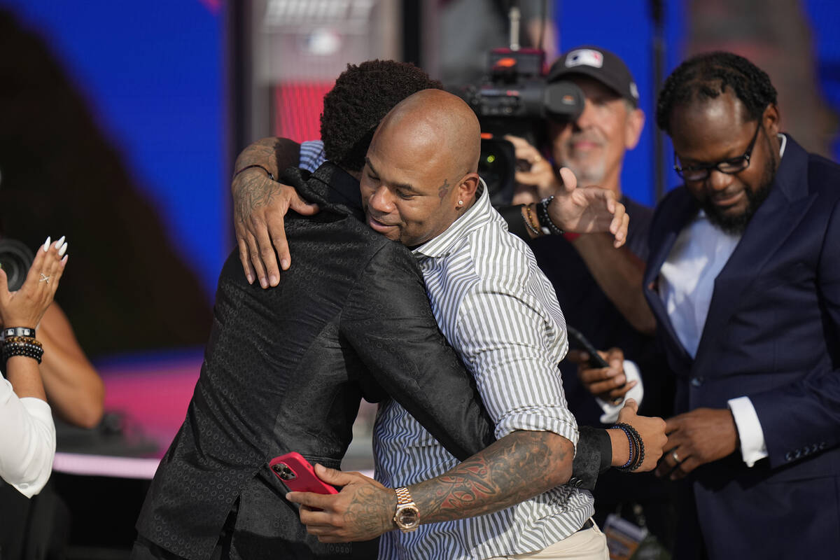 Justin Crawford, left, is hugged by his father, former MLB player Carl Crawford, after being se ...