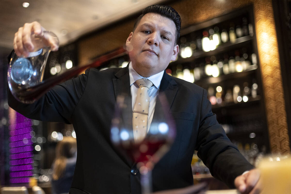 Sommelier Erick Ramirez pours wine from a decanter at La Cave Wine and Food Hideaway in Wynn La ...