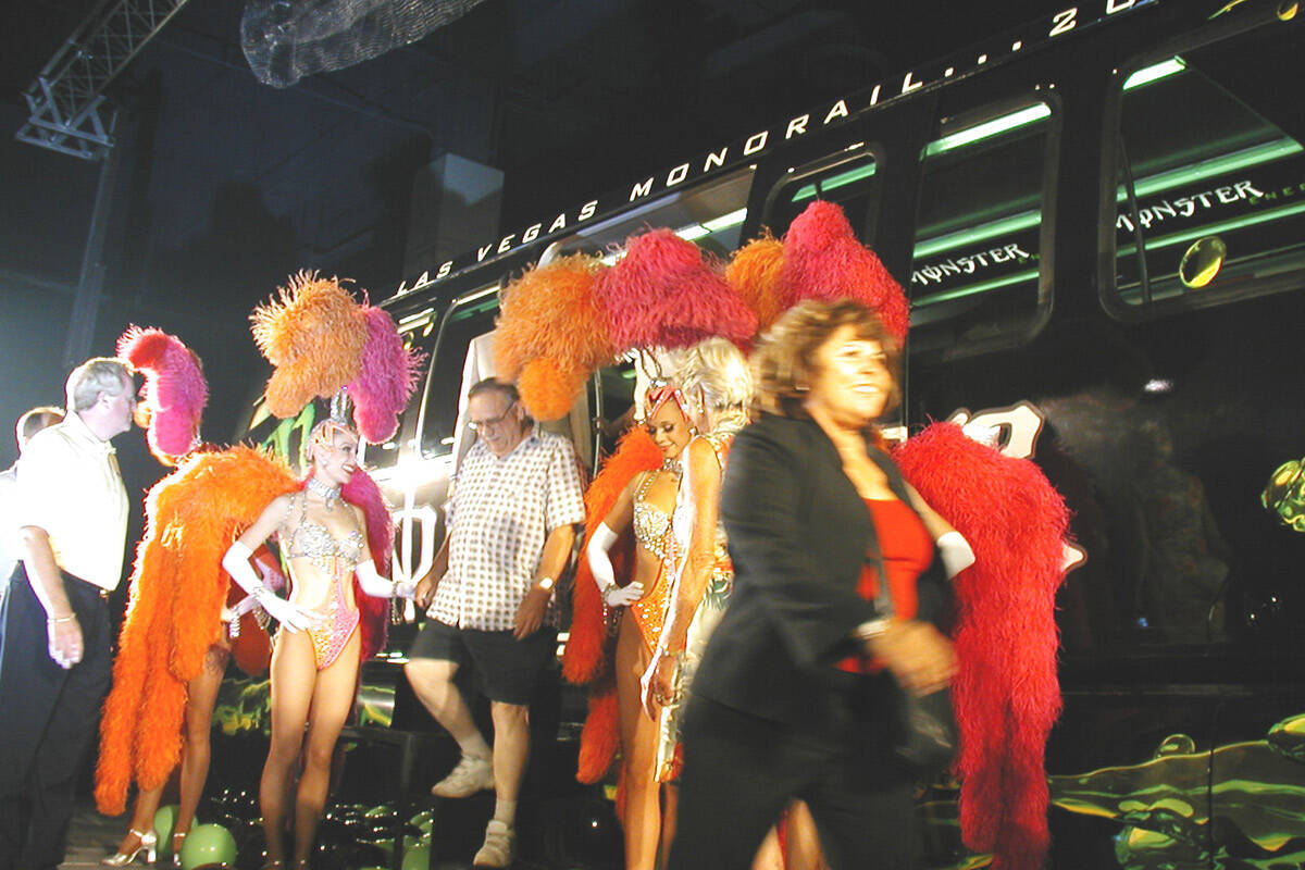 Bally's showgirls offer a hand to people exiting the first Las Vegas monorail train on June 24, ...