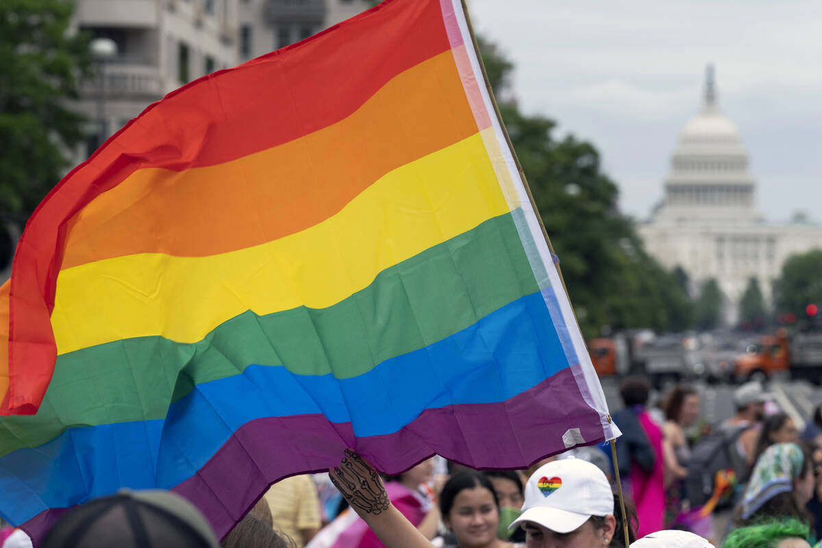 FILE - With the U.S. Capitol in the background, a person waves a rainbow flag as they participa ...