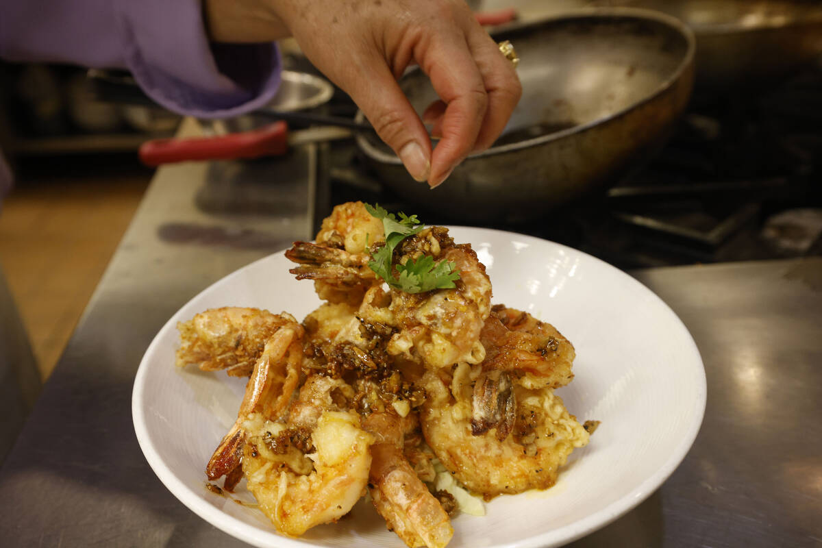 Lotus of Siam owner/chef Saipin Chutima garnishes a dish of garlic prawns, Friday, July 22, 202 ...
