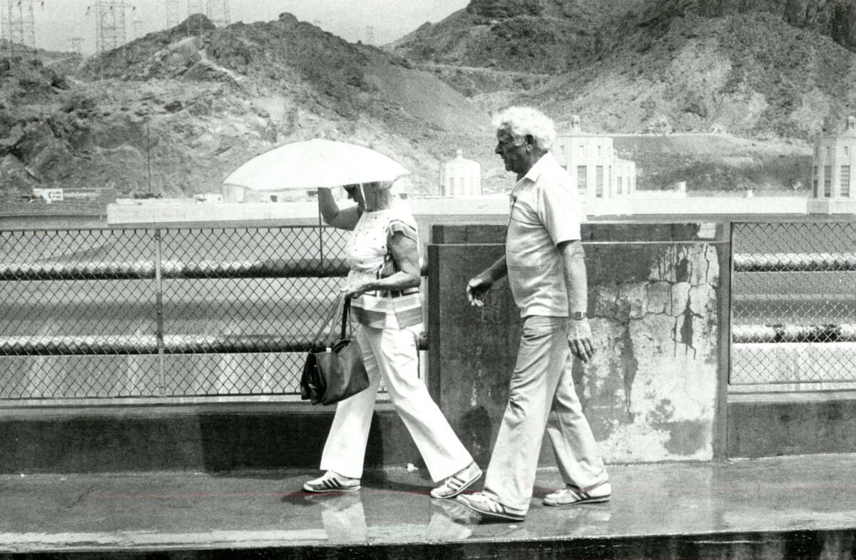 Tourists walk along the Arizona side of the spillway at the Hoover Dam on July 21, 1983. The fo ...