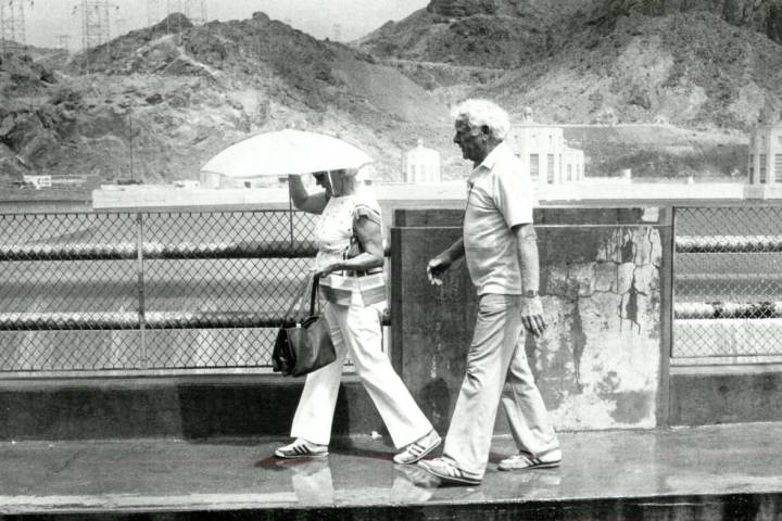 Tourists walk along the Arizona side of the spillway at the Hoover Dam on July 21, 1983. The fo ...