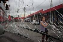A woman looks at a trolleybus damaged by Russian shelling at Barabashovo market in Kharkiv, Ukr ...