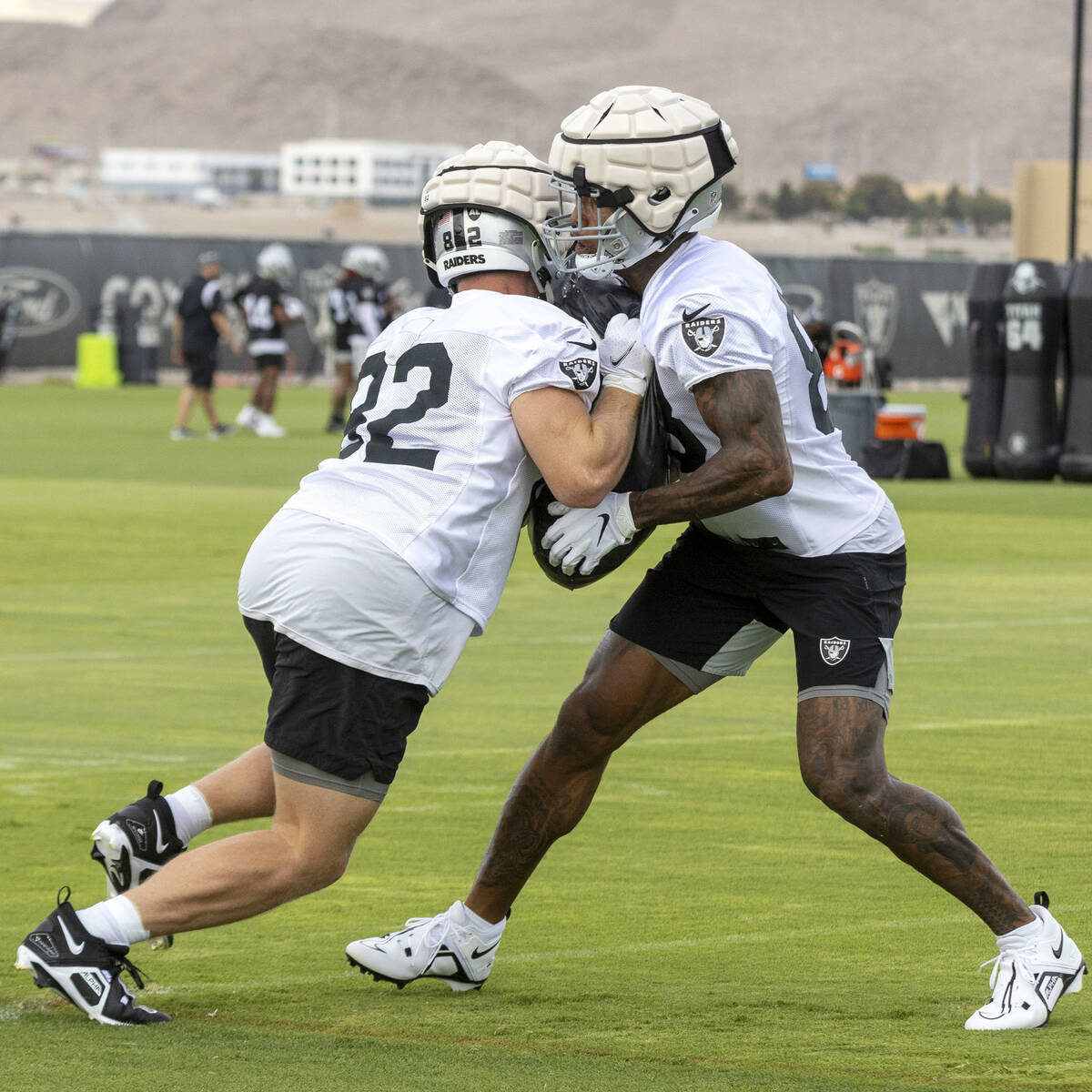 Raiders tight end Darren Waller (83) holds pads as tight end Nick Bowers (82) rushes him during ...