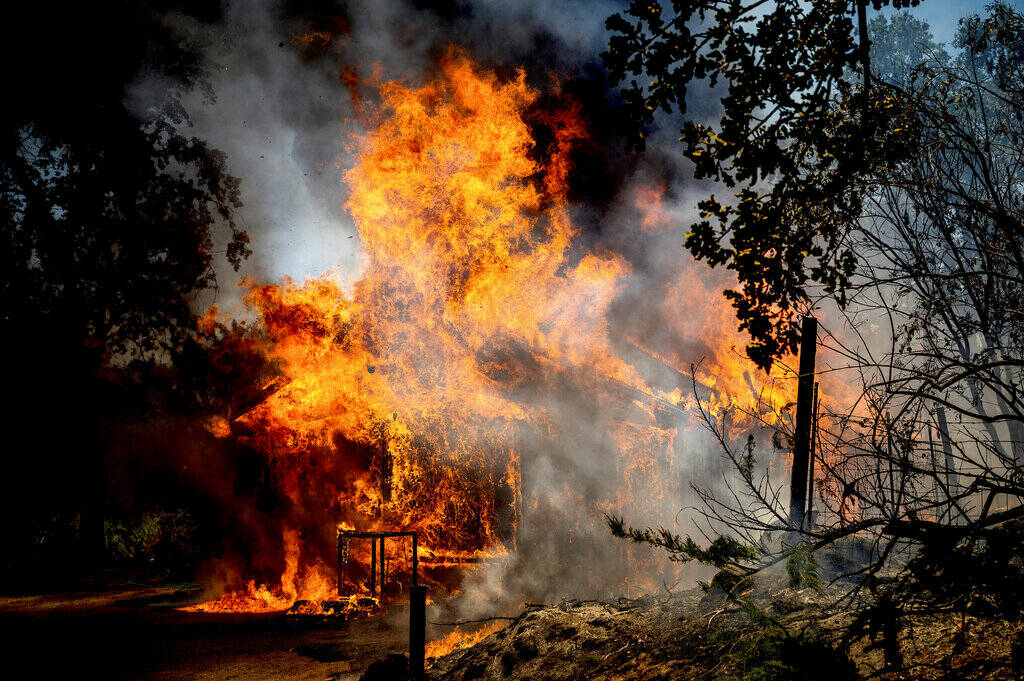 Flames from the Oak Fire consume a home on Triangle Road in Mariposa County, Calif., Saturday, ...
