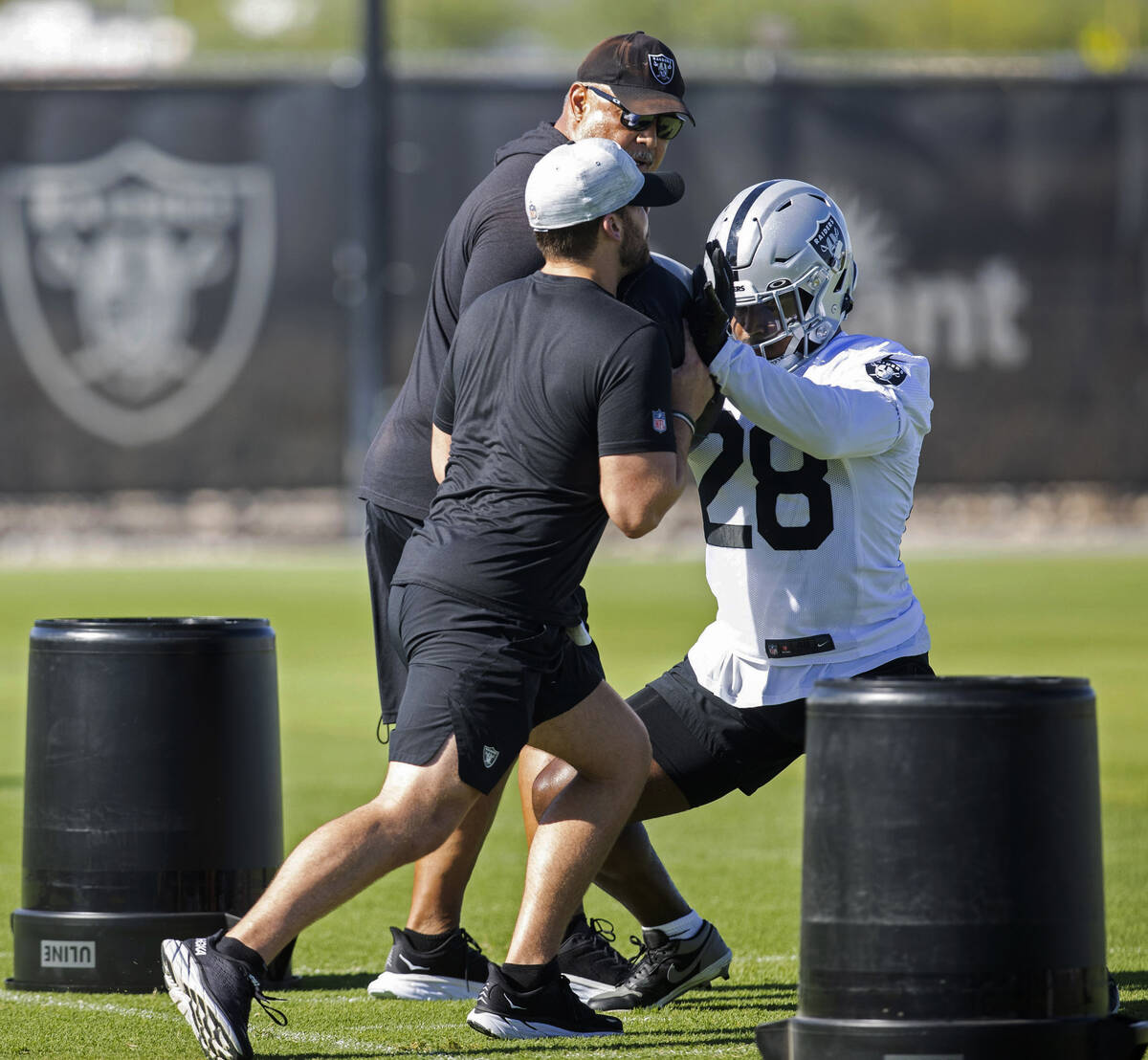Raiders running back Josh Jacobs (28) runs through a drill as running backs coach Kennedy Polam ...
