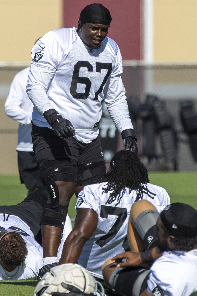 Raiders offensive guard Lester Cotton, Sr. (67) speaks to offensive guard John Simpson (76) du ...