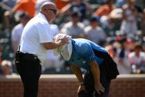 Baltimore Orioles head trainer Brian Ebel, left, helps home plate umpire Scott Barry get relief ...