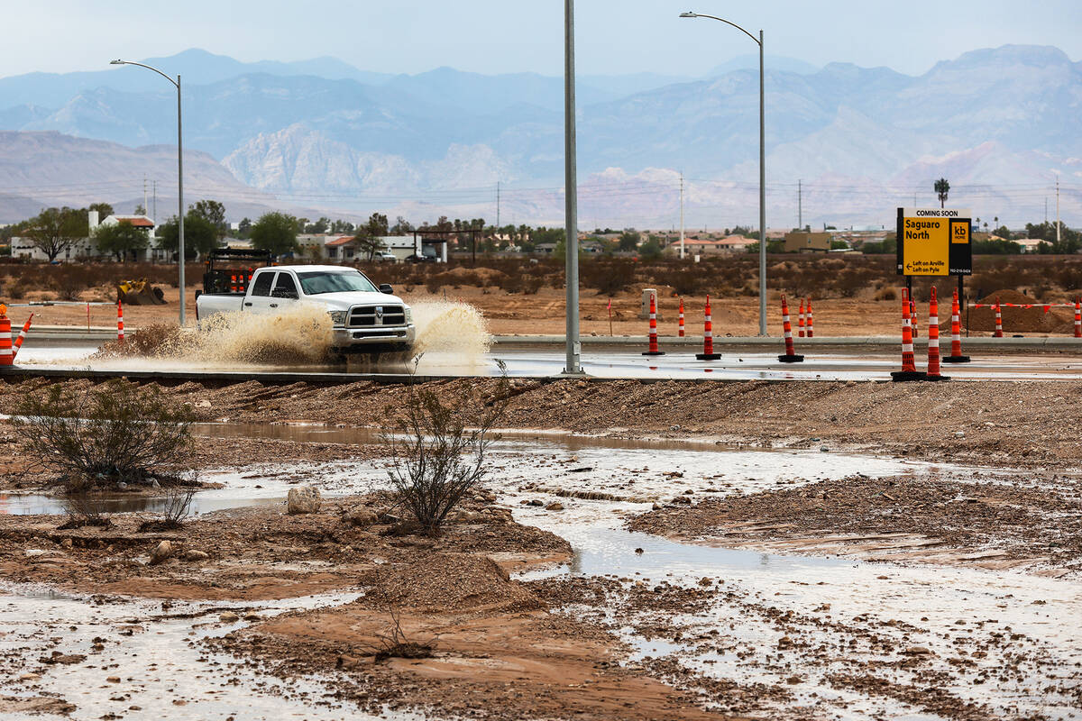 Cars drive through a flooded road on Silverado Ranch Boulevard in Las Vegas, Monday, July 25, 2 ...