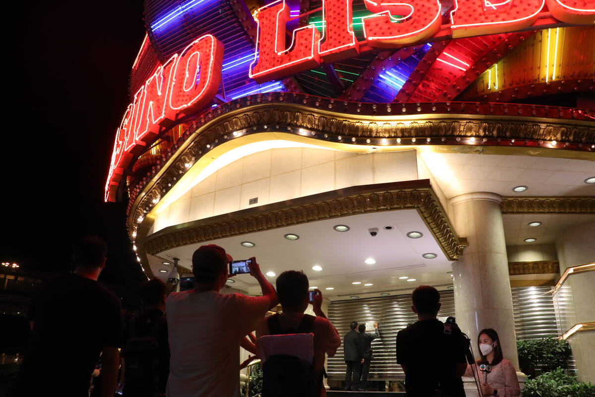 People take photos as security closes the shutters at Casino Lisboaʡt midnight on Monday, July ...