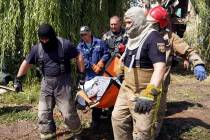 Rescuers move a covered body of a woman killed by Russian missile attack on Monday in Chuhuiv, ...