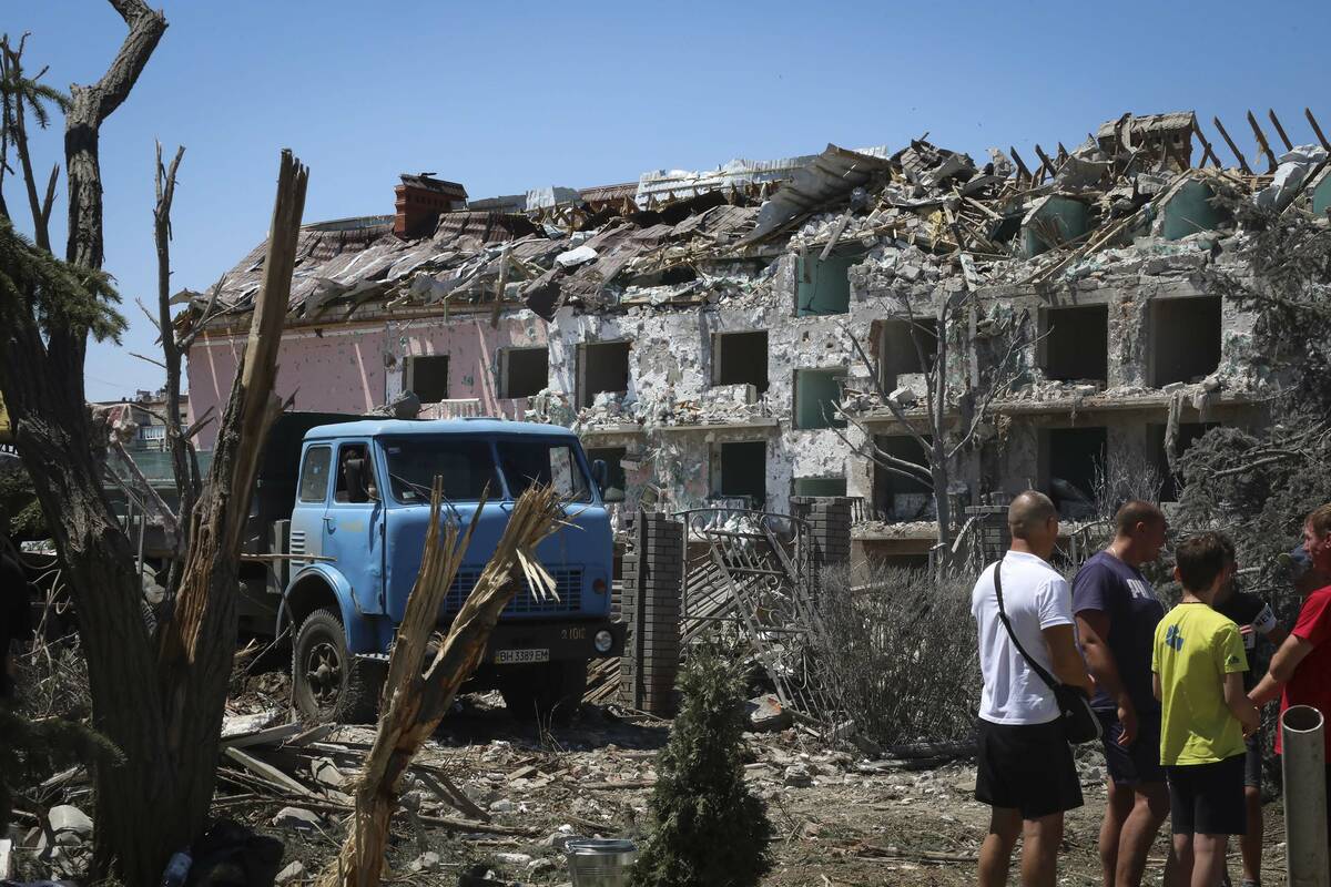 FILE - Local residents stand next to damaged residential building in the town of Serhiivka, loc ...