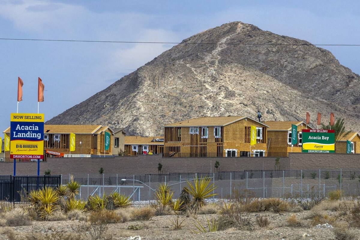 A roofer works on new home construction at Acacia Landing with Lone Mountain behind on Wednesda ...