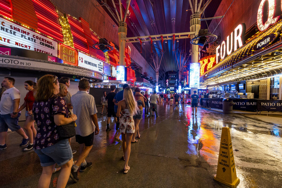 People navigate the rainy walkways as some power is out at the Fremont Street Experience as a p ...