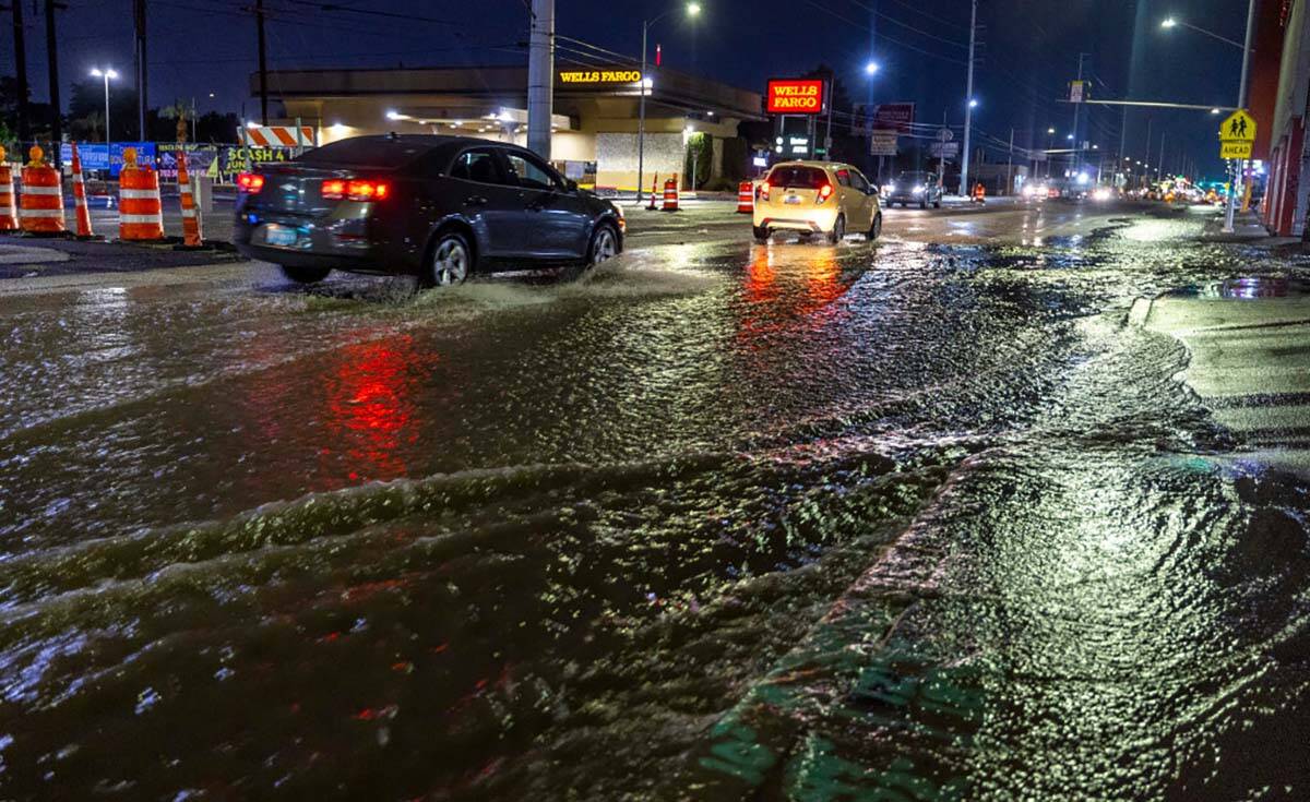 Cars navigate the flooded Charleston Blvd. at South Spencer Street as a powerful storm moves th ...