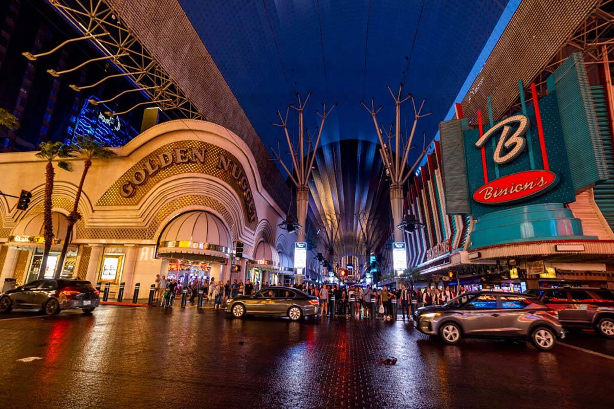 People navigate the rainy walkways as some power is out on the canopy and some casino fronts at ...