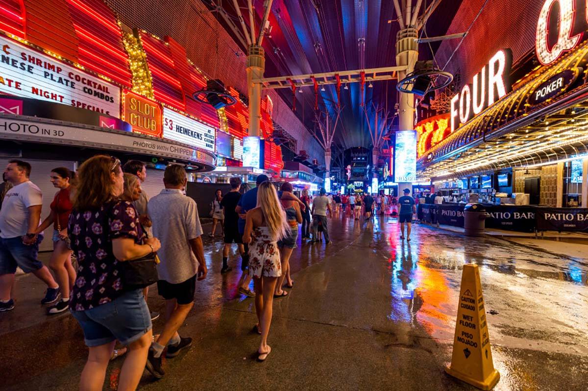 Orang-orang menavigasi jalur hujan saat listrik padam di Fremont Street Experience sebagai…