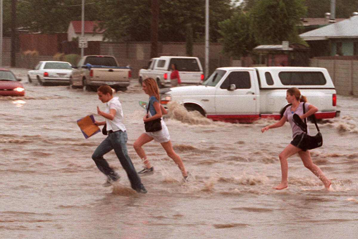 Schoolchildren cross a flooded street near Washington Avenue and Pecos Road on July 8, 1999. (L ...