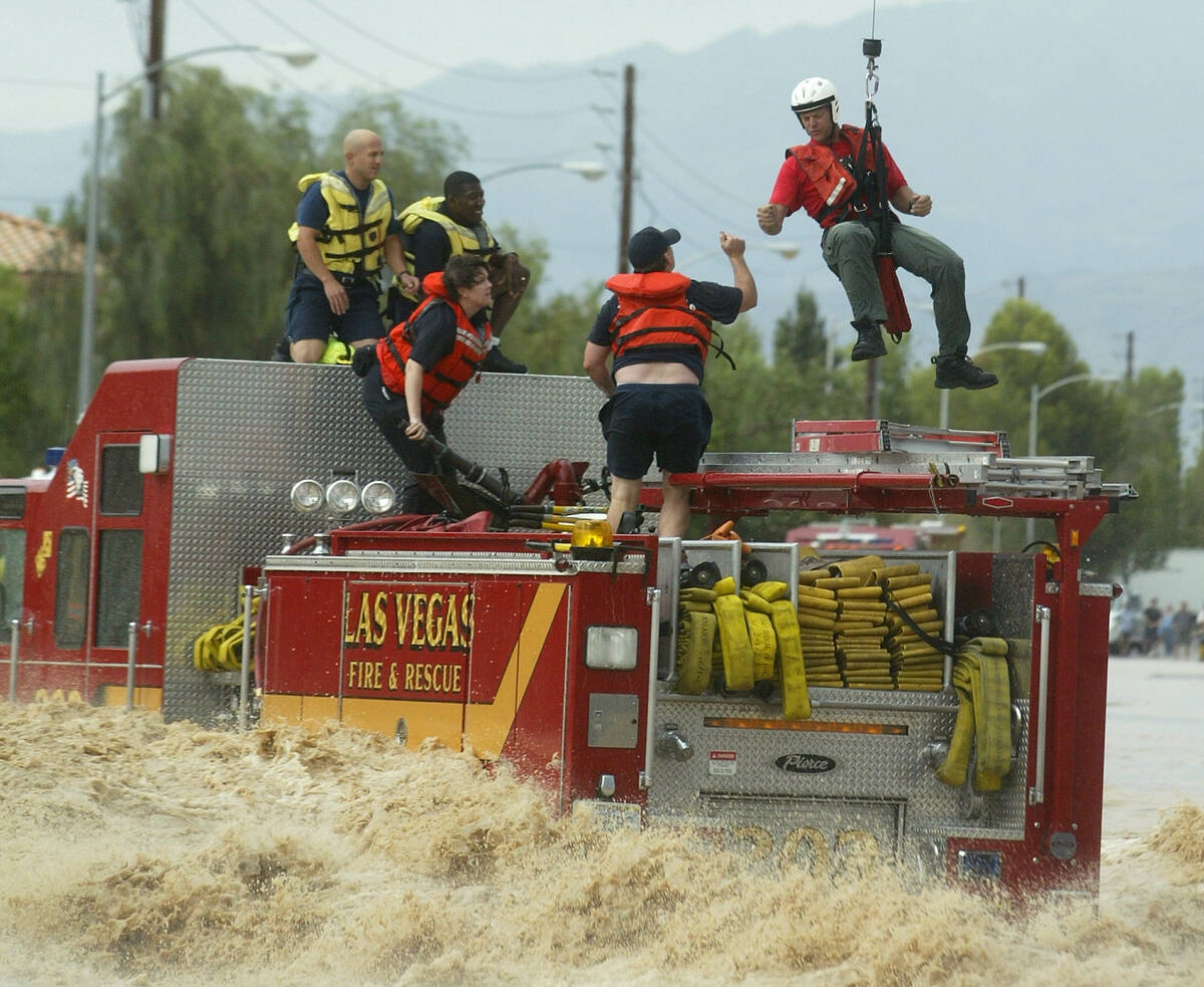 Members of the Las Vegas Fire and Rescue Department are rescued off a fire truck caught in floo ...