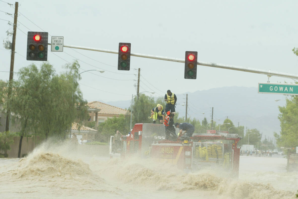 Firefighters are rescued from the fire truck at the flooded intersection of Rainbow Boulevard a ...
