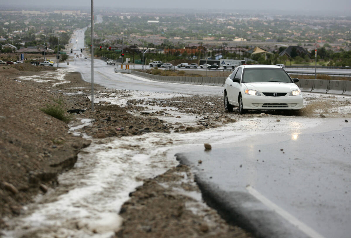 Rainwater floods the shoulder and crosses Lone Mountain Road west of the 215 Beltway during an ...