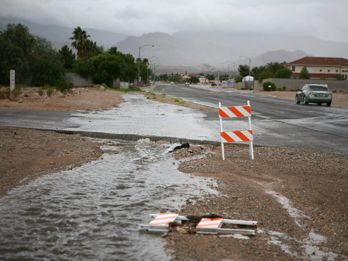Rainwater floods the shoulder of Lone Mountain Road and crosses Al Carrison Street during an af ...