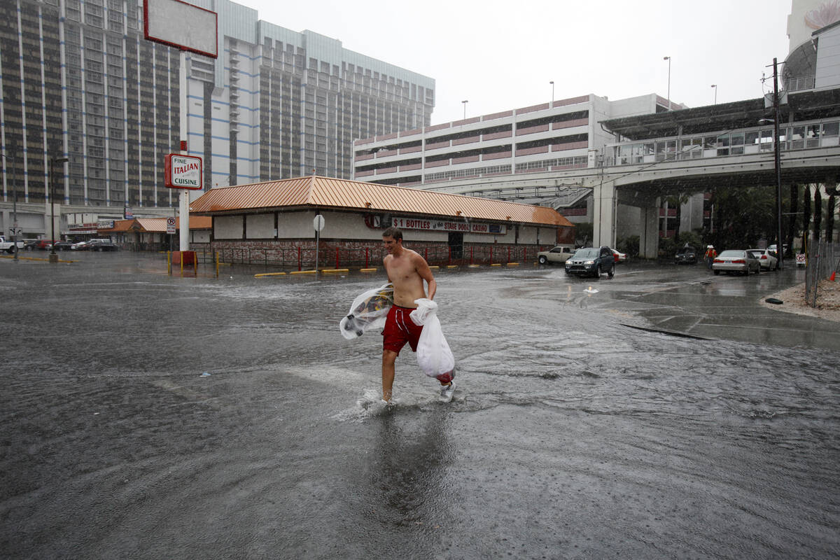 Taylor Bradley walks across a flooded street behind the Flamingo hotel and casino in Las Vegas ...