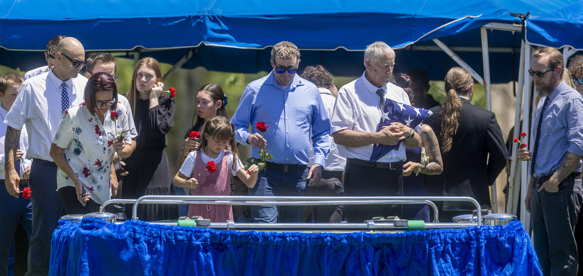 Family members and friends take turns tossing roses onto the casket of Southern Nevada WW II ve ...