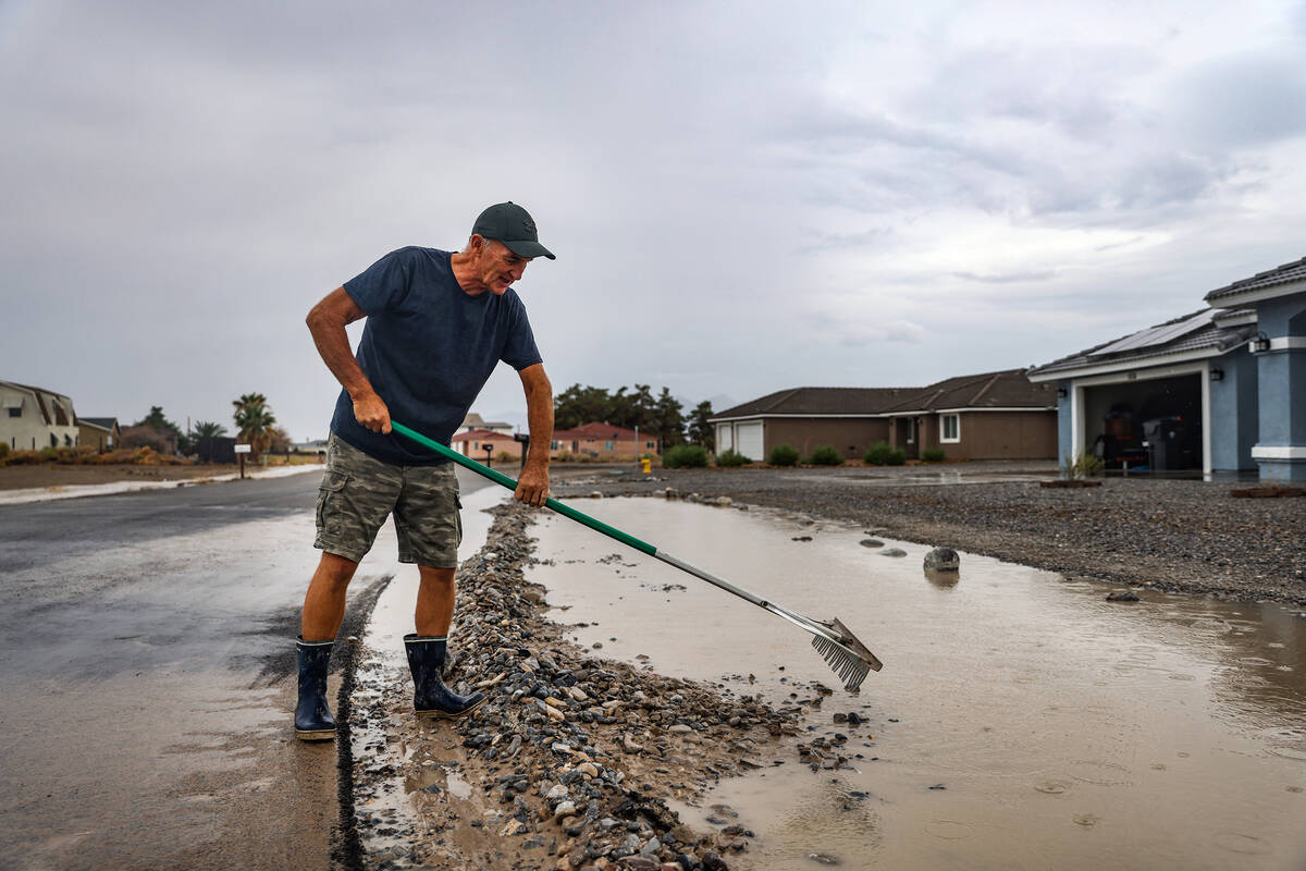Lonny Young diverts water on his street after a flash flood hit the region in Pahrump, Nev., Su ...