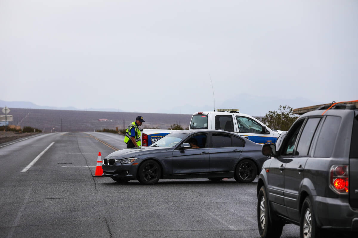 Gary Howes, with the Nye County Sheriff’s department auxiliary team, guides traffic away ...