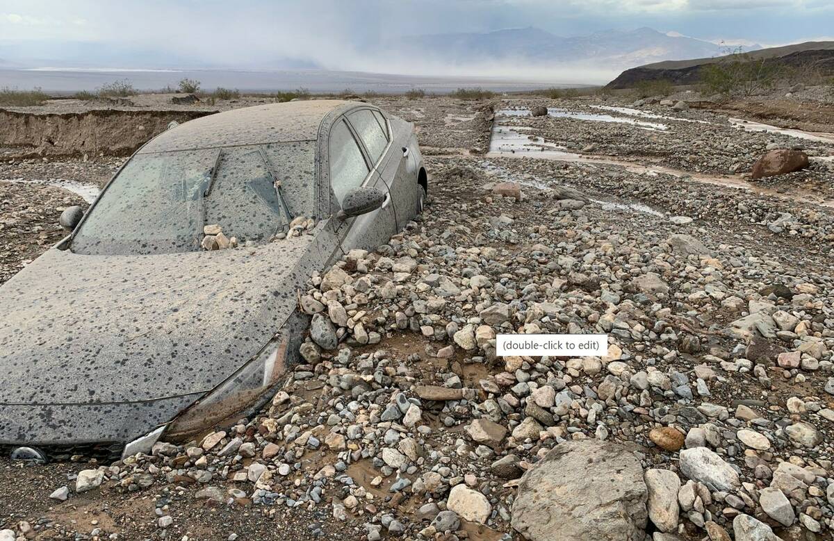 A car is partially covered in debris off Highway 190 near Stovepipe Wells in Death Valley Natio ...