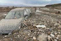 A car is partially covered in debris off Highway 190 near Stovepipe Wells in Death Valley Natio ...